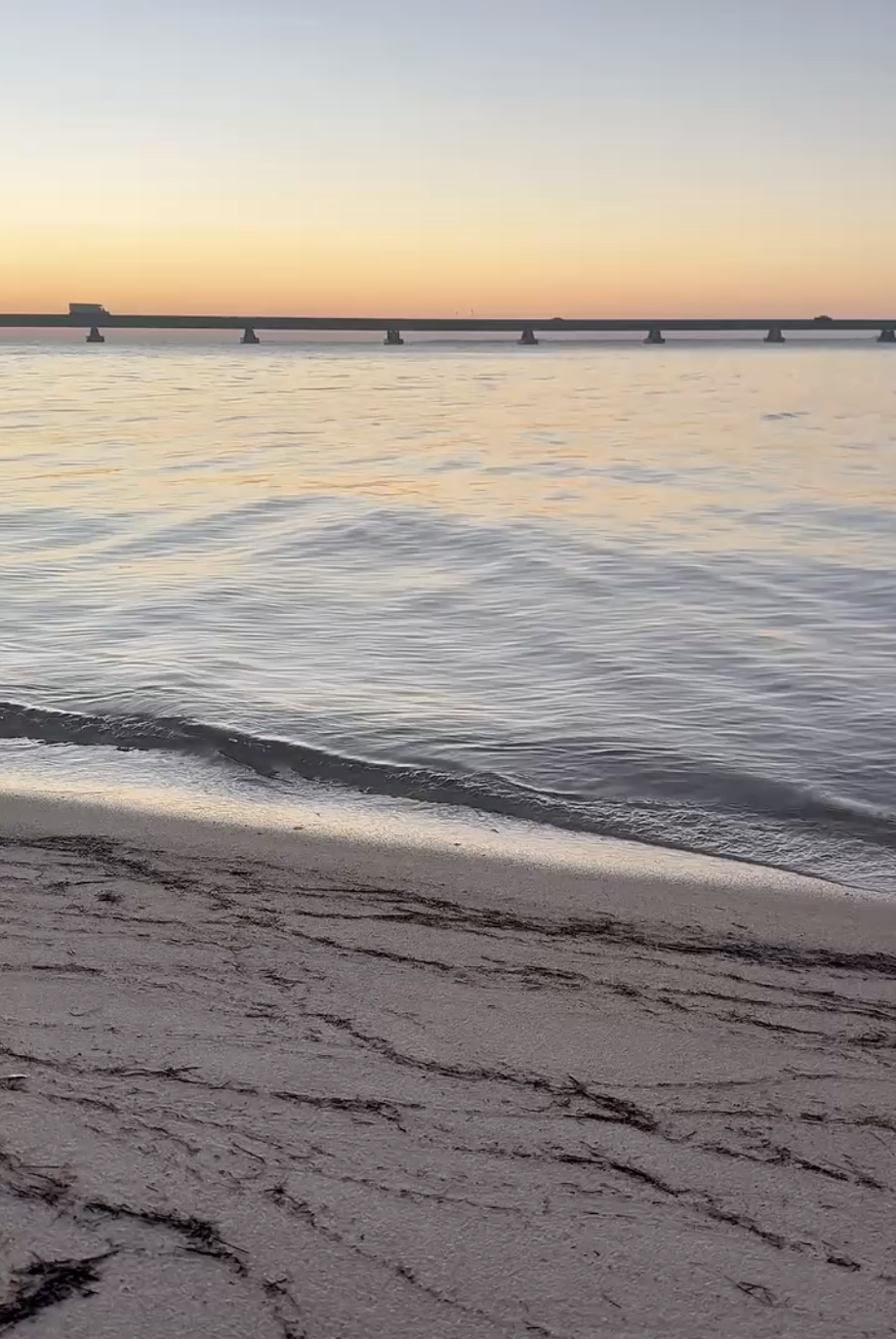 A calm sunset over the water and a bridge on Florida's Emerald Coast, featured in a guide to signs a special needs child is ready to potty train.