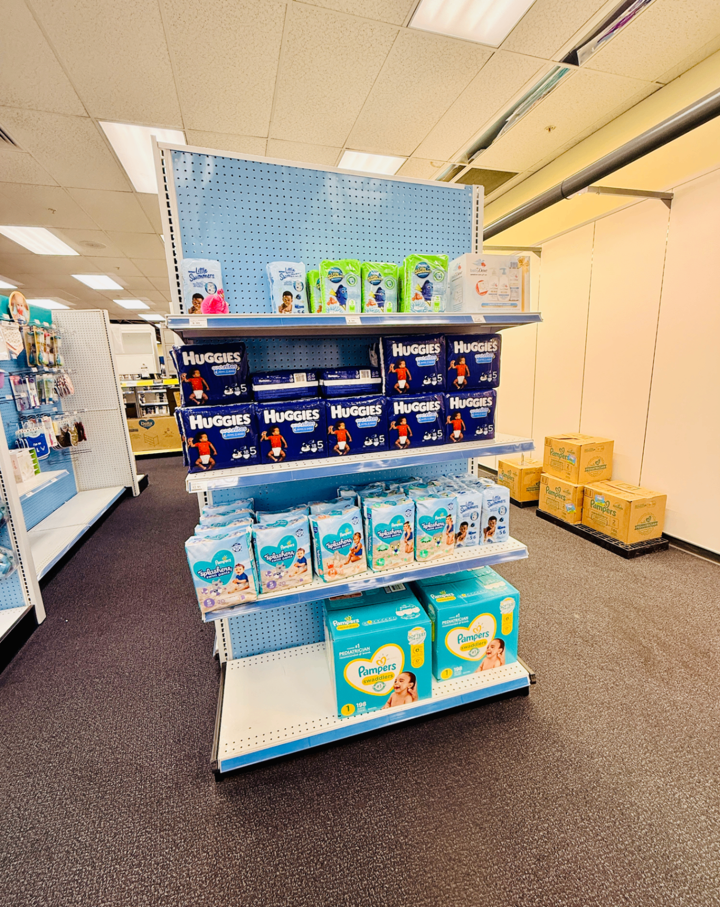 A store end-cap stocked with diapers, swim diapers, and pull-ups in various brands and sizes