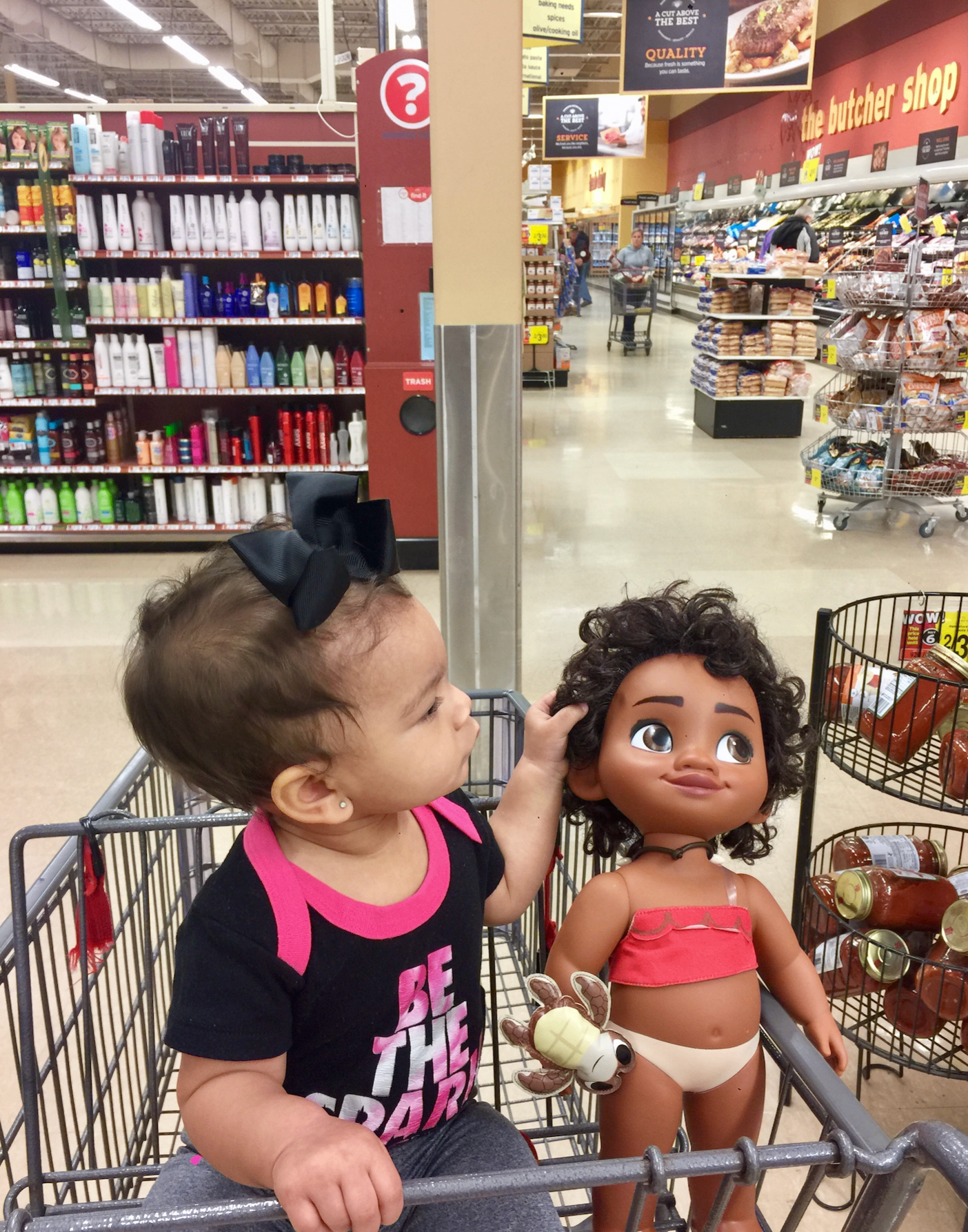 A baby sitting in a shopping cart at the grocery store, featured in a guide to how much baby wipes cost.