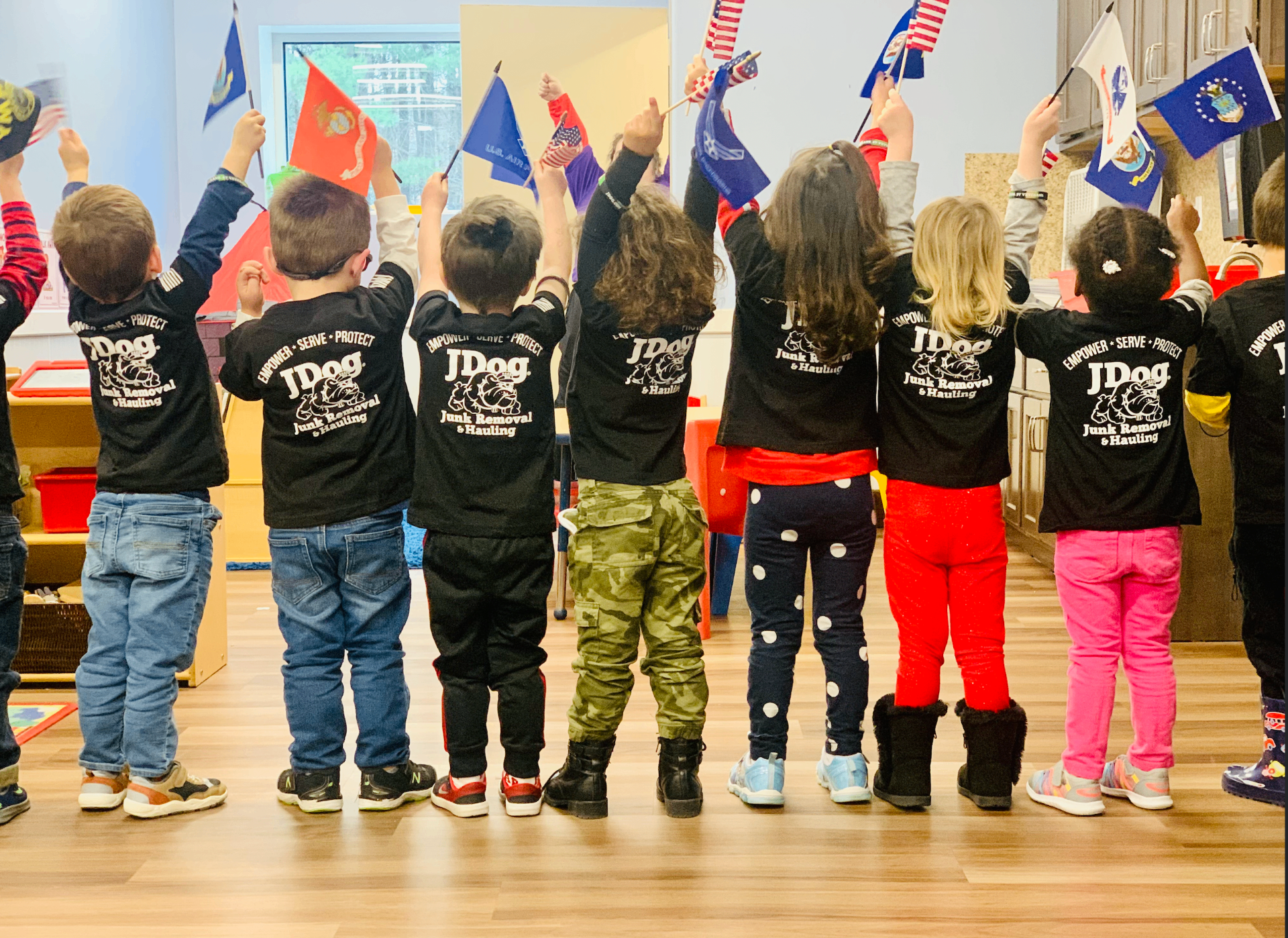 Toddlers waving flags in a daycare classroom, featured in a guide to how many diapers to bring to daycare or the CDC.