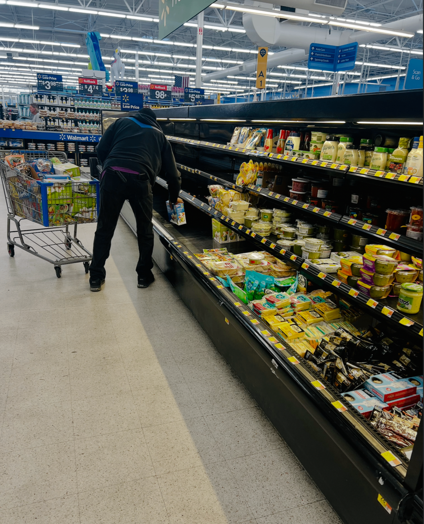 A shopper with a cart of diaper boxes in a Walmart grocery aisle